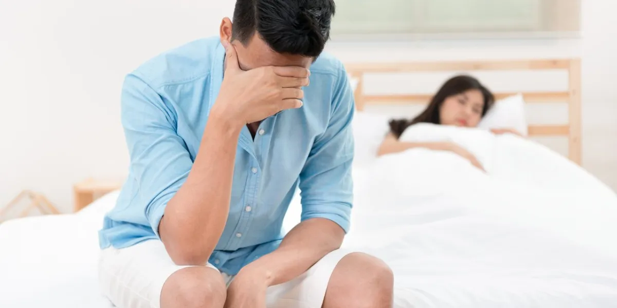 husband unhappy and disappointed in the erectile dysfunction during sex while his wife sleeping on the bed sexual problems in men
