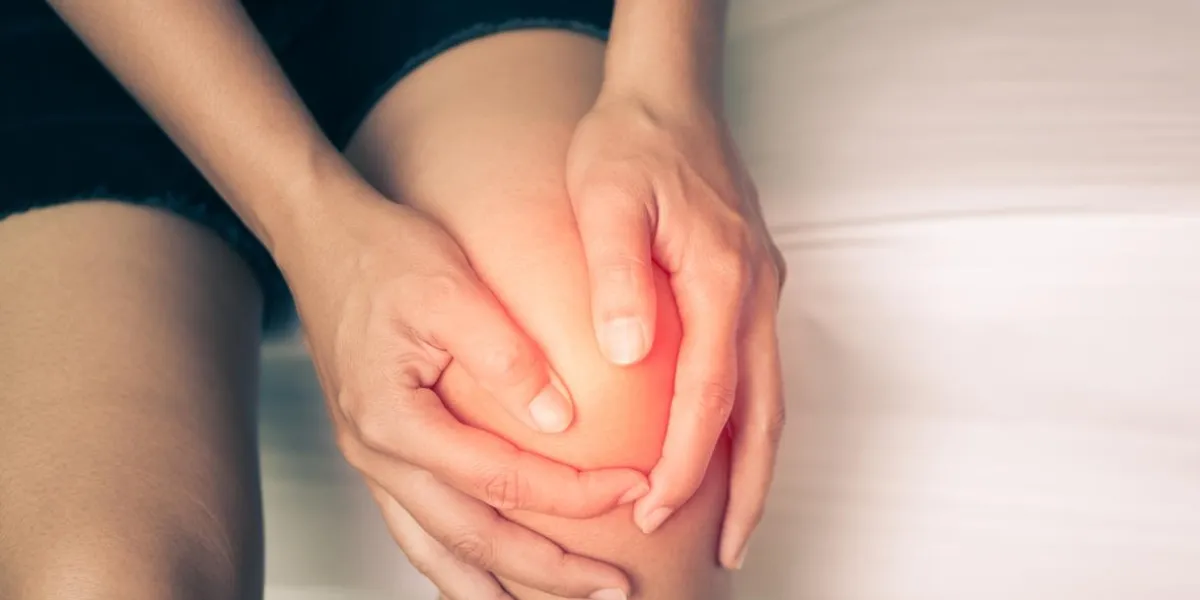 black and white of young woman massaging her painful knee, medical and health care concept