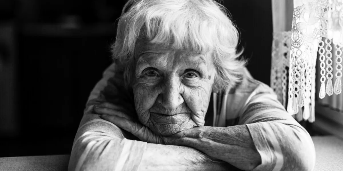 close-up black and white portrait of a old woman at the table in home