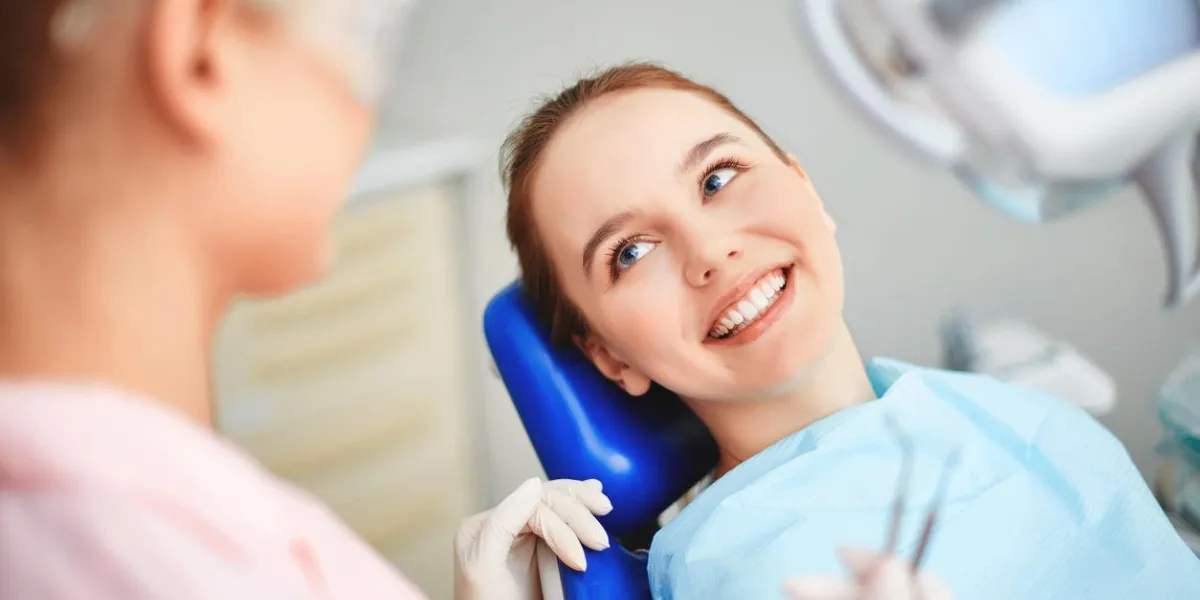 jeune femme assise dans un cabinet de dentiste et en regardant son médecin avec le sourire