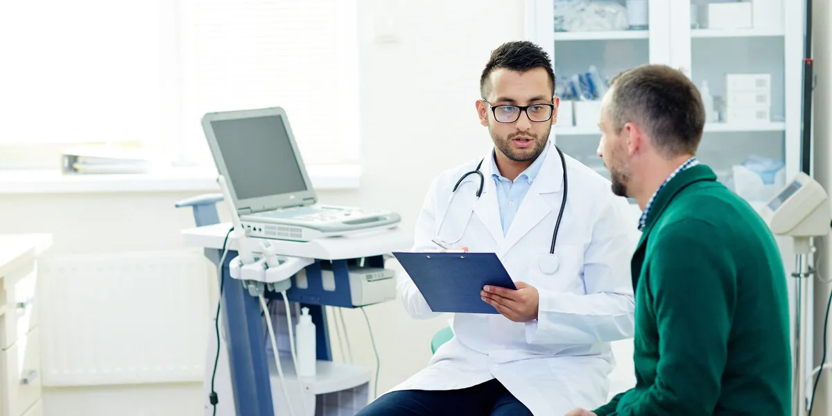 middle-aged bearded patient having consultation with highly professional physician at modern office, they discussing diagnosis and possible treatment
