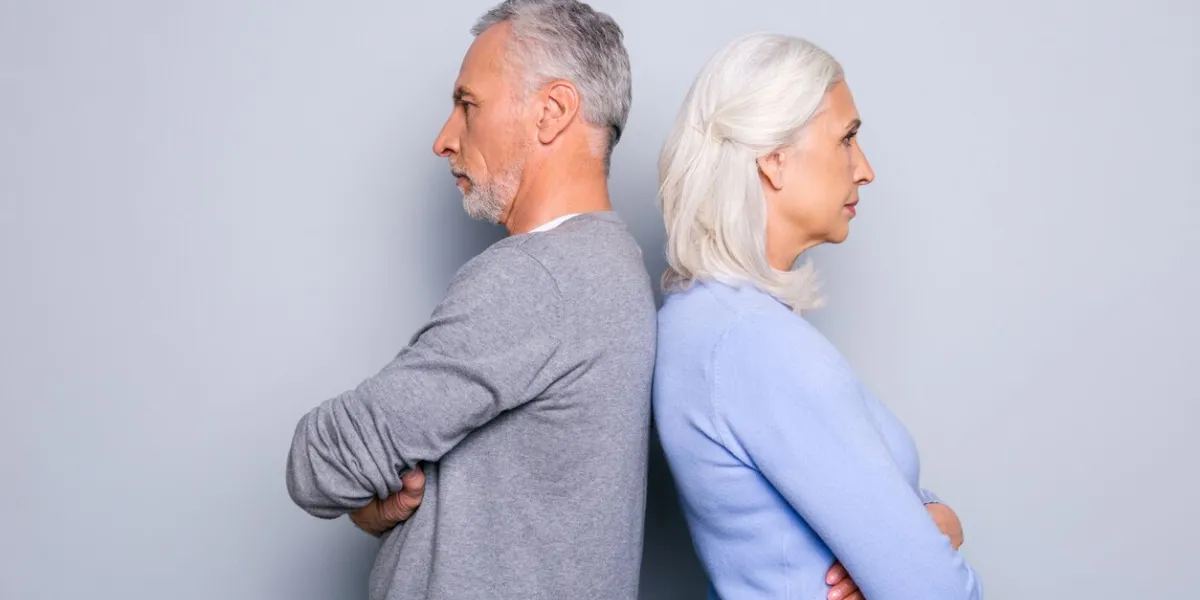 concept of misunderstanding and communicative problem between two senior people, they are standing back to back, isolated on grey background