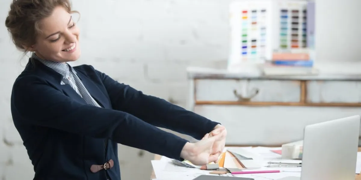 portrait de jeune femme souriante portant costume assis à la maison bureau de bureau en face de l'ordinateur portable, qui s'étend avec plaisir après le travail est fait, en regardant l'écran avec une expression heureuse