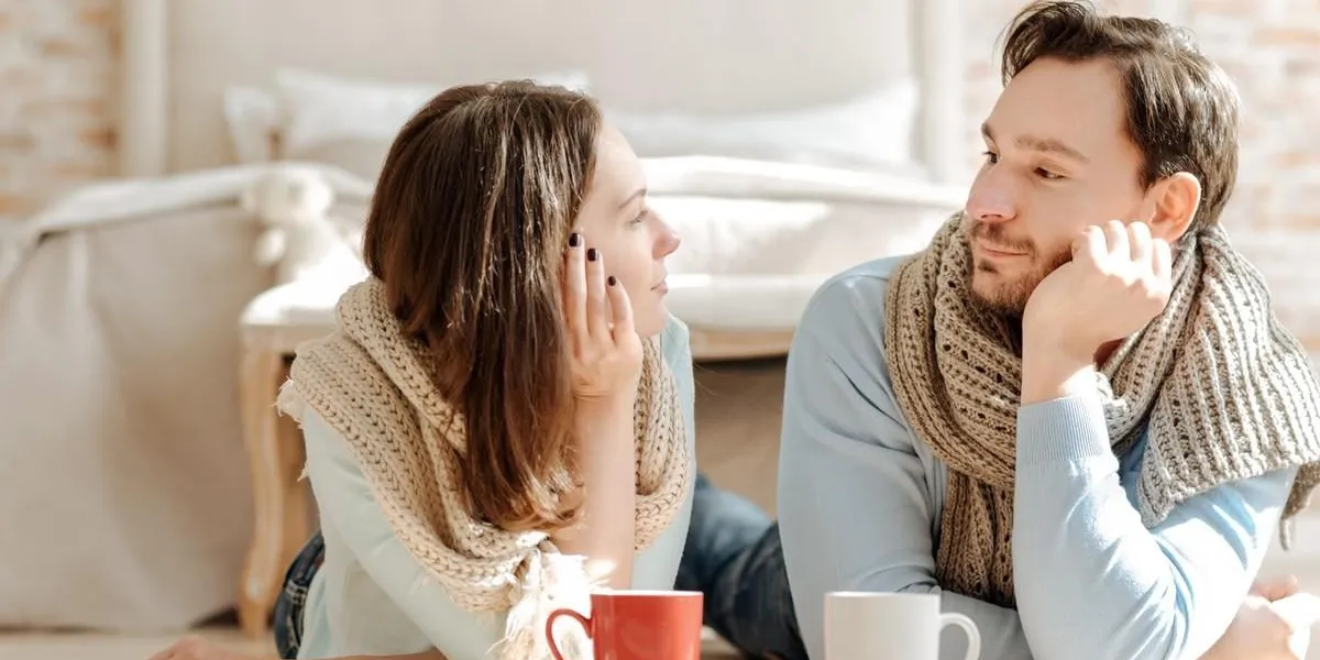 love you peaceful infatuated young couple lying on the floor at home while expressing love and drinking hot tea