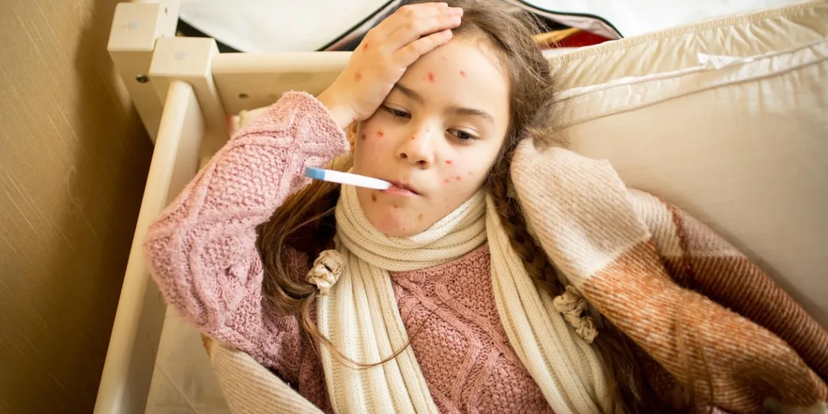 portrait d'une fille malade avec la varicelle couché dans son lit et la mesure de la température