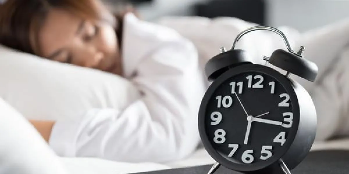 femme asiatique, dormir sur le lit et se réveiller avec réveil