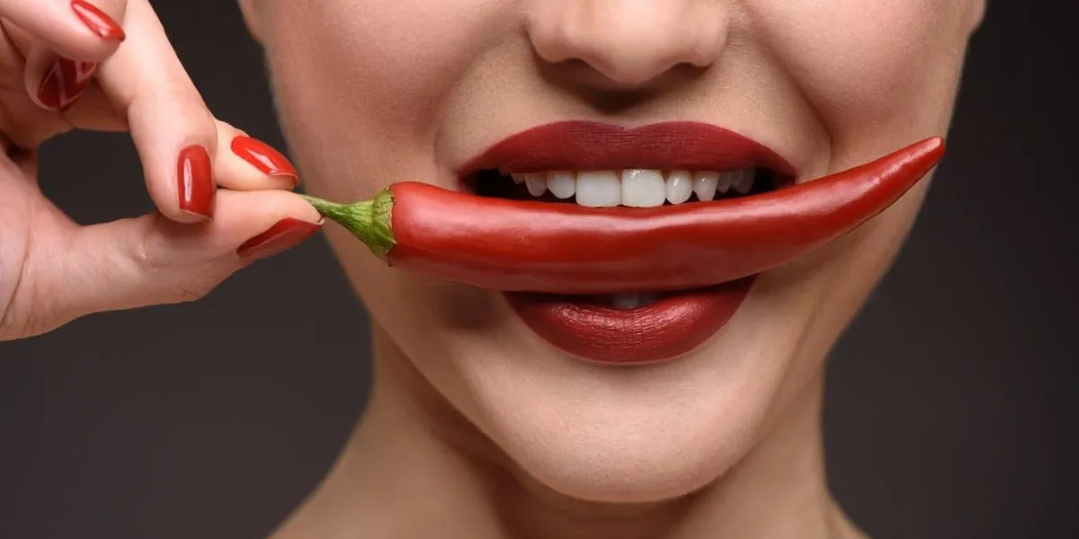 close up of sexy young girl biting spicy red pepper with desire