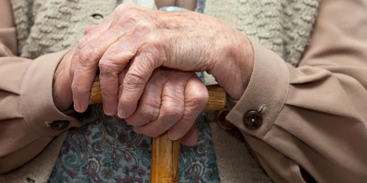 hands of elderly woman resting on staff