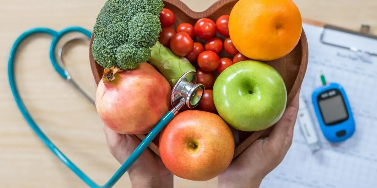 diabetes monitor, cholesterol diet and healthy food eating nutritional concept with clean fruits in nutritionist's heart dish and patient's blood sugar control record with diabetic measuring tool kit