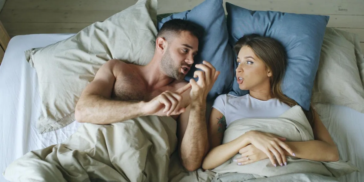 top view of young couple lying in bed upset and arguing each other