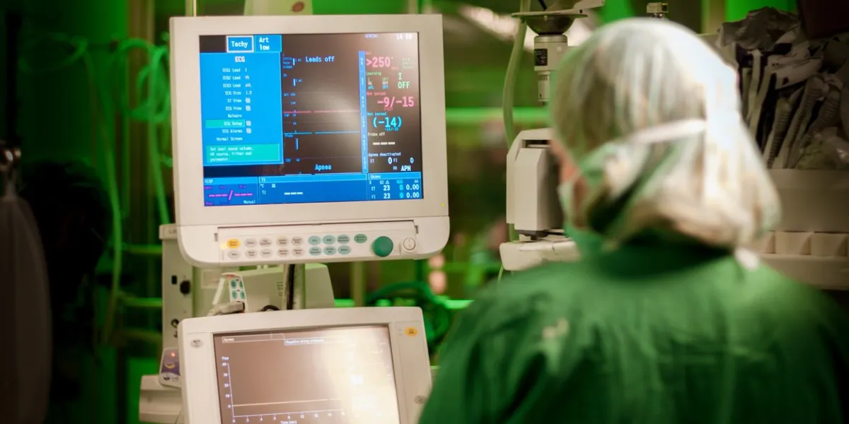 female anesthesiologist at monitor in operation surgery room with green lights on