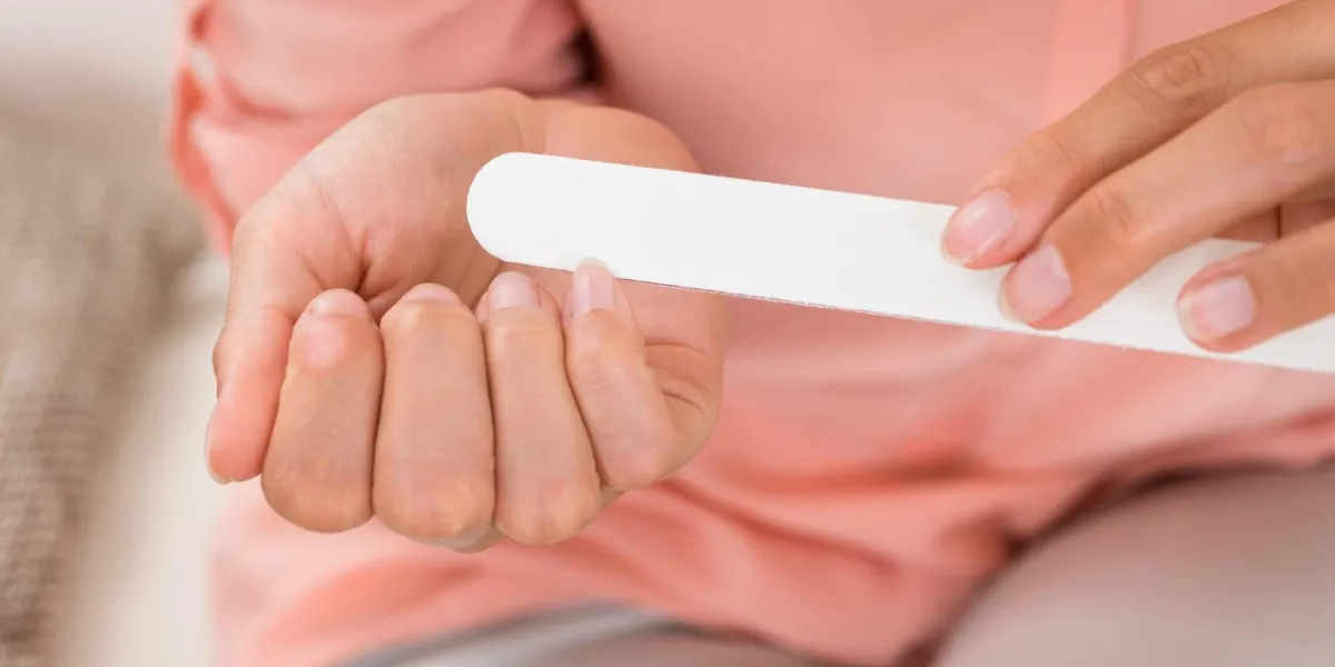 gros plan photo de mains de femme limant des ongles