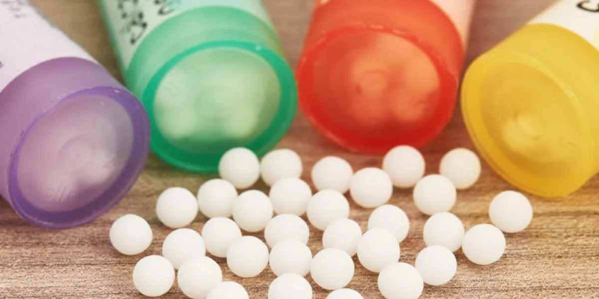 globules homéopathiques dispersés avec leurs récipients colorés en forme de tube sur une table en bois