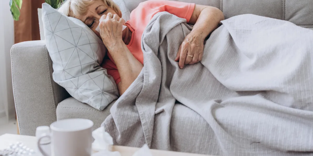 senior woman being sick having flu lying on sofa sick older lady lying in bed with high fever