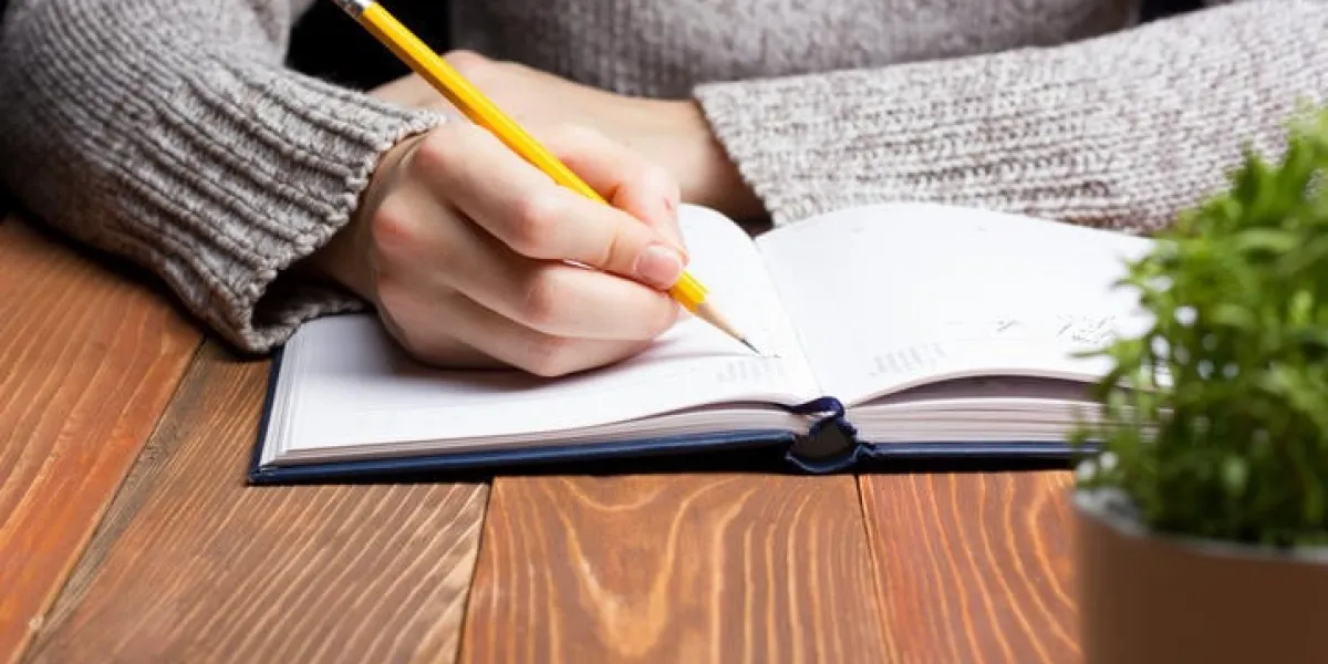 mains féminines avec un crayon écrivant sur ordinateur portable