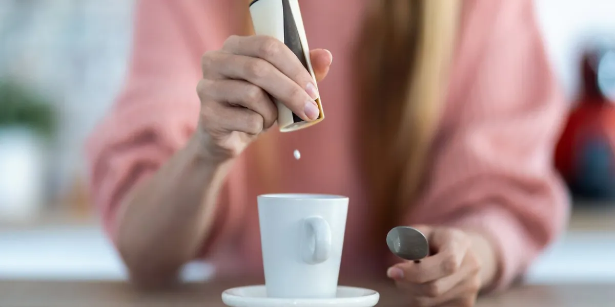 close-up of woman hand throwing saccharin pills on coffee cup in the kitchen at home