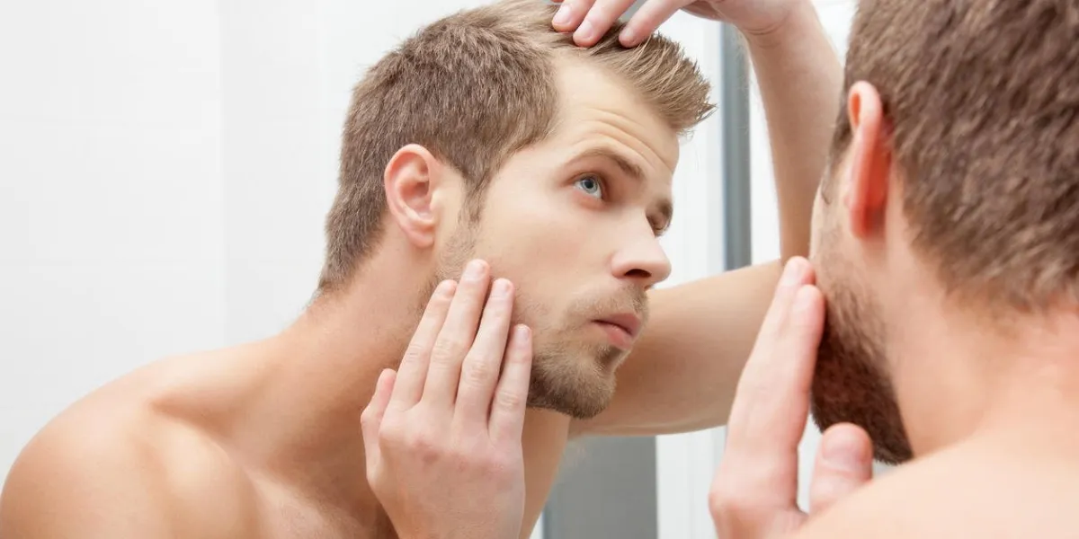 homme debout devant le miroir, s'inquiéter de la perte de cheveux