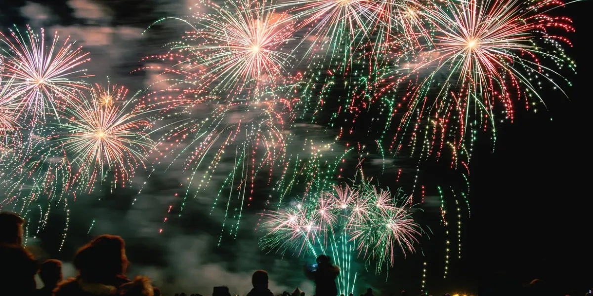 big fireworks with silhouetted people in the foreground watching