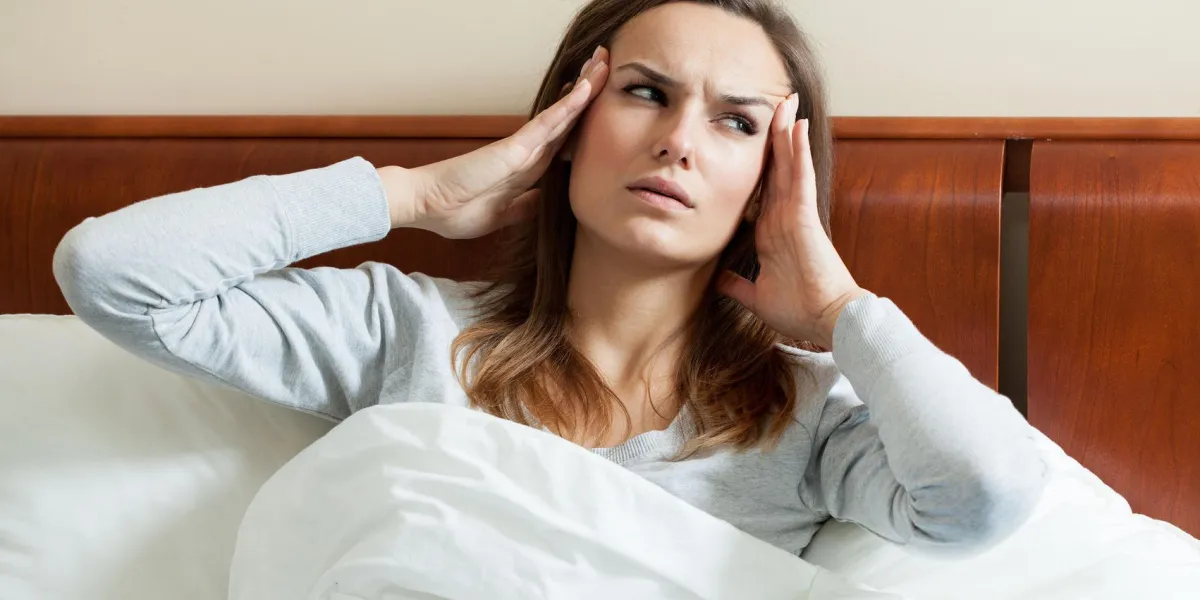 image de femme ayant la migraine au lit