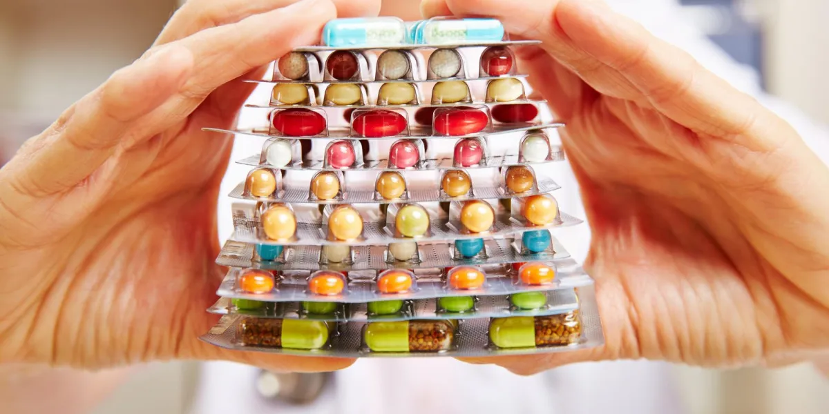 mains du docteur tenant de nombreux comprimés et médicaments en pile