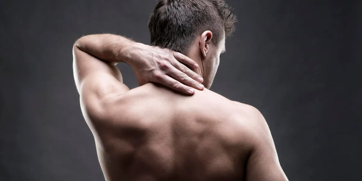 pain in the neck man with backache muscular male body handsome bodybuilder posing on gray background low key close up studio shot middle part of the body