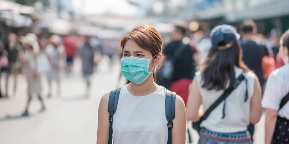 young asian woman wearing protection mask against novel coronavirus (2019-ncov) or wuhan coronavirus at chatuchak weekend market, landmark and popular for tourists attractions in bangkok, thailand