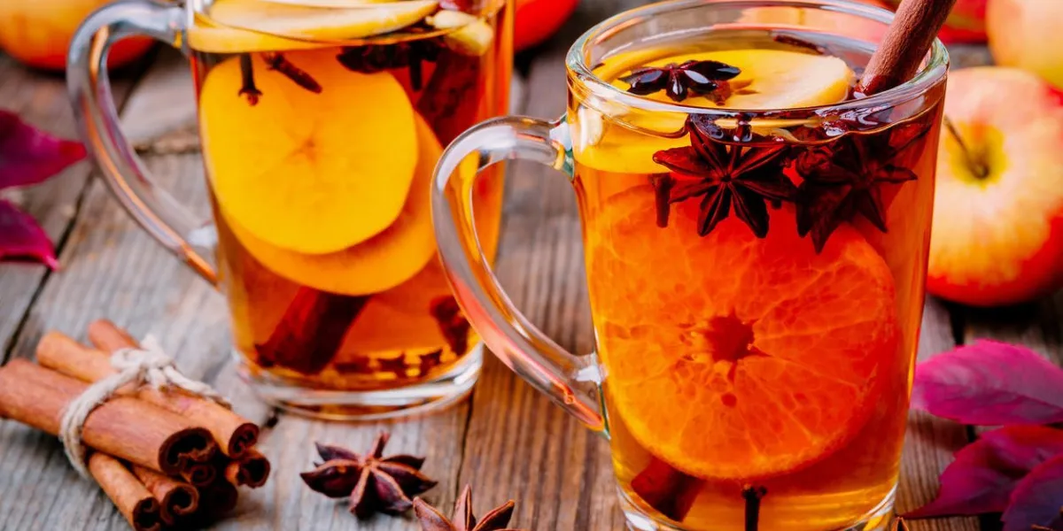 cidre de pomme chaud chaud avec des bâtons de cannelle, clous de girofle et anis sur fond en bois