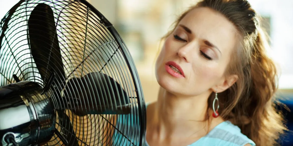 relaxed modern housewife in the modern house in sunny hot summer day enjoying freshness in the front of fan