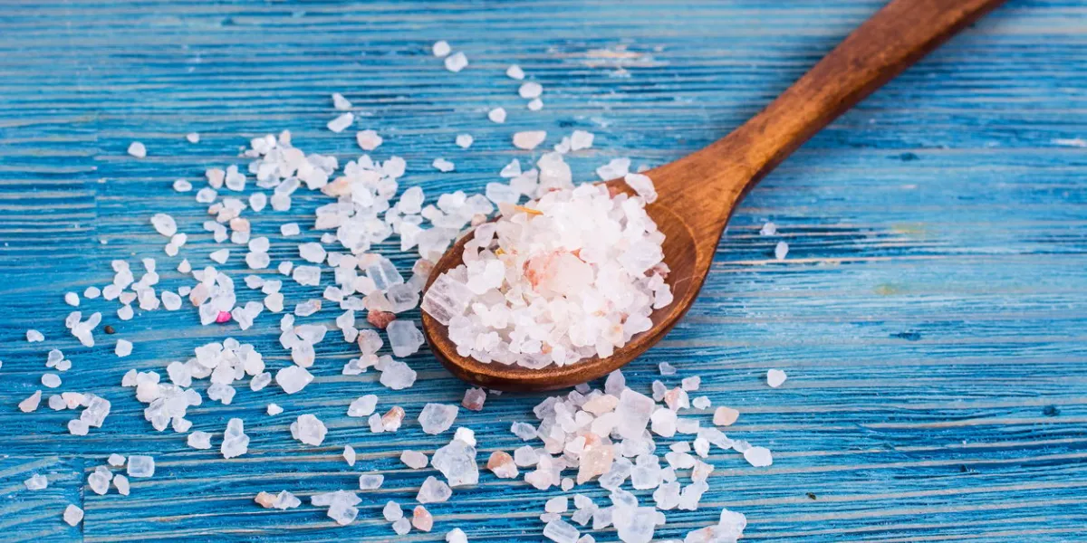 large pink sea salt on blue background studio photo
