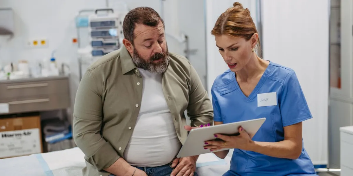 female doctor consulting with the overweight patient, discussing test result in doctor office obesity affecting middle-aged men's health concept of health risks of overwight and obesity