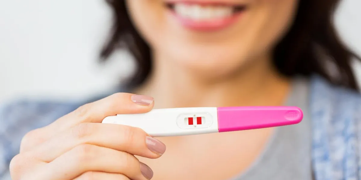 pregnancy, fertility, maternity and people concept - close up of happy woman with positive home pregnancy test