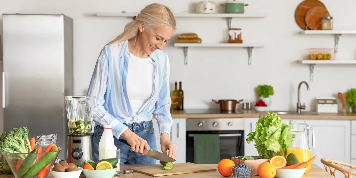 mature,woman,cutting,cucumber,for,healthy,smoothie,in,kitchen