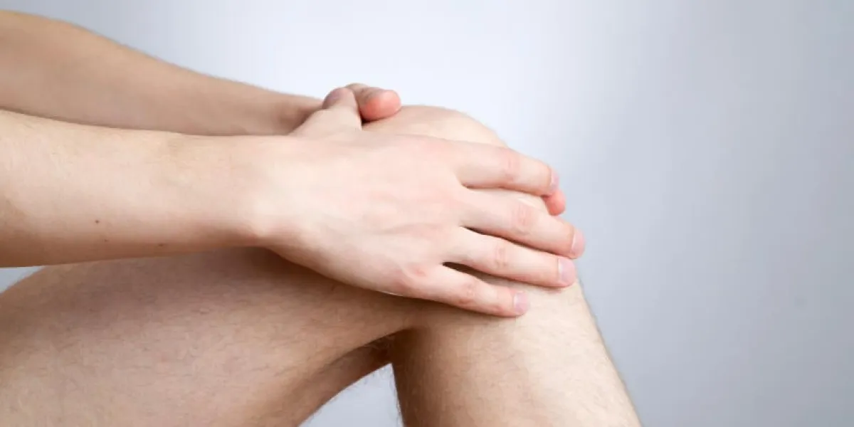 douleur au genou chez les hommes sur fond gris