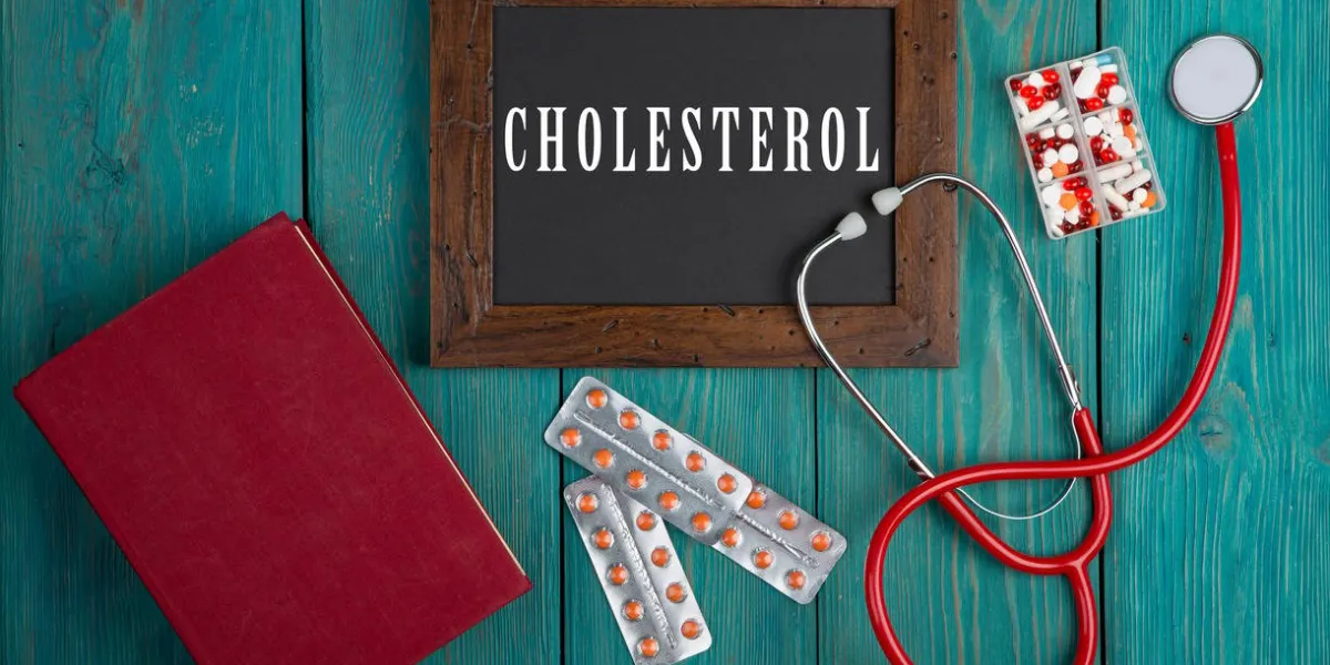 medecine concept - blackboard with word cholesterol, stethoscope, book, pills on blue wooden background
