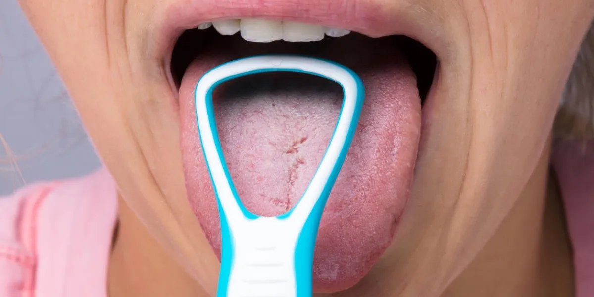 close-up of young woman cleaning tongue with cleaner