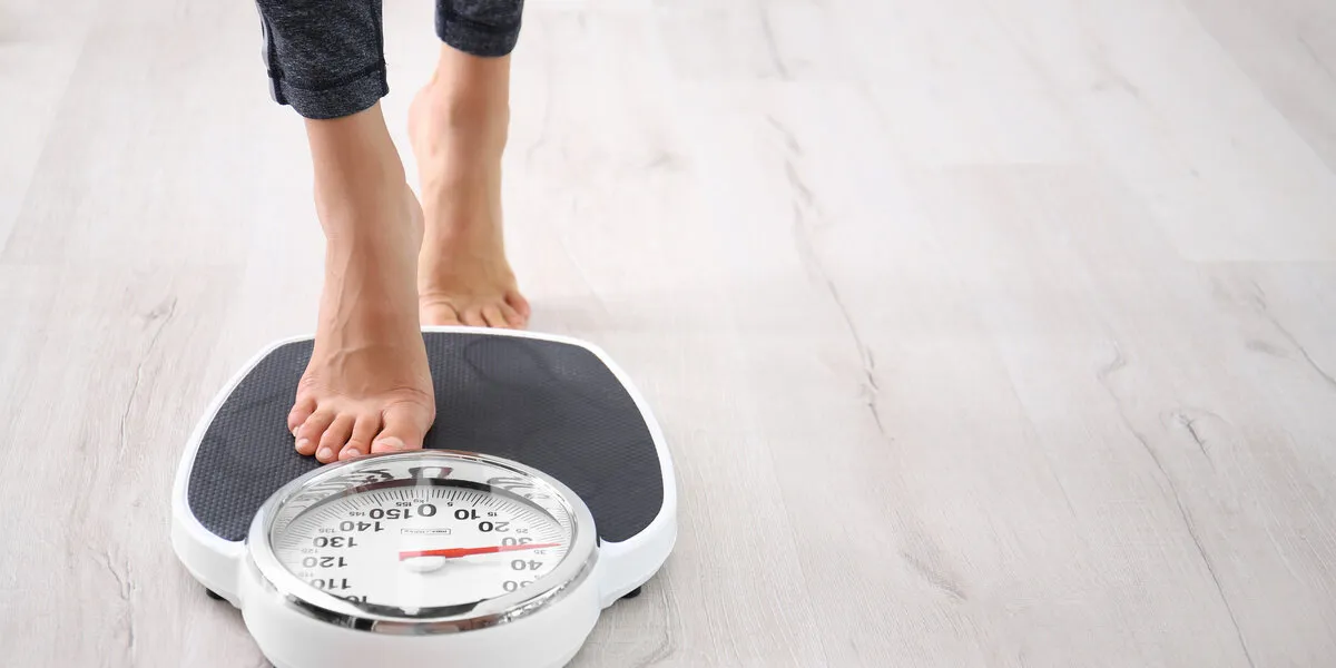woman measuring her weight using scales on floor