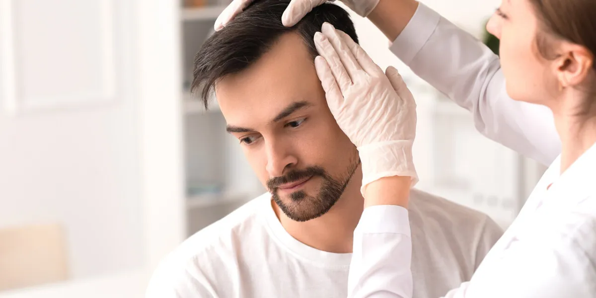 doctor examining young man's hair in clinic, closeup