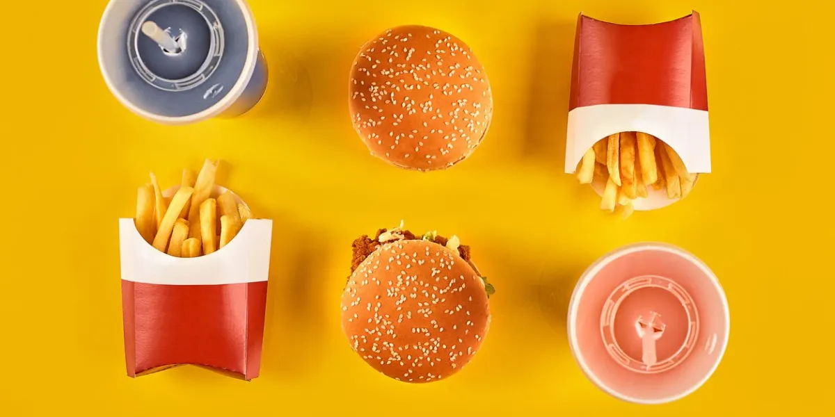 fast food and unhealthy eating concept - close up of fast food snacks and cold drink on yellow background top view copy space still life flat lay