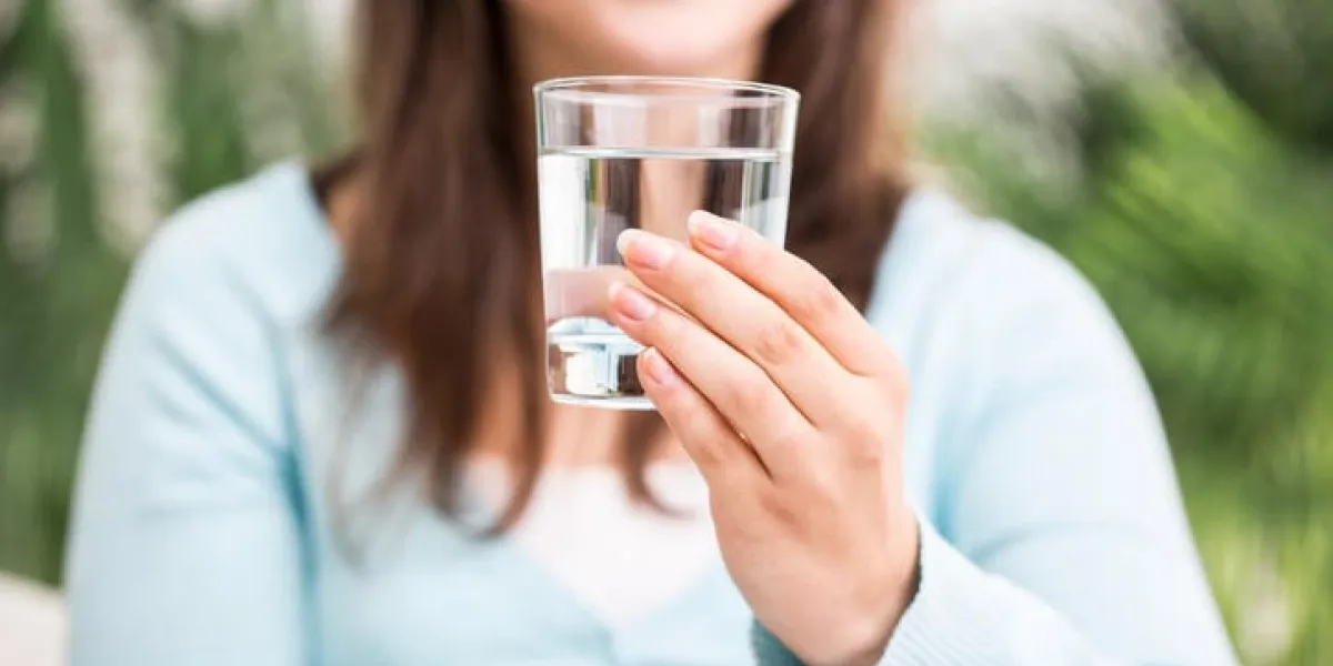 gros plan d'un verre d'eau propre, image floue d'une femme en arrière-plan