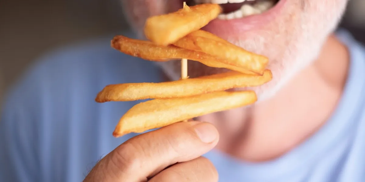 close up on caucasian man mouth eating french fries and enjoy it a lot - fried potato unhealthy food makes people happy