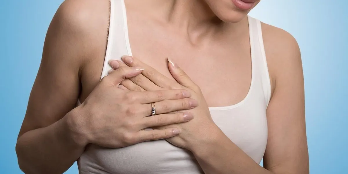 closeup cropped portrait young woman with breast pain touching chest colored isolated on blue background