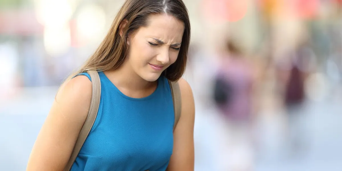 single woman suffering belly ache outdoors in the street