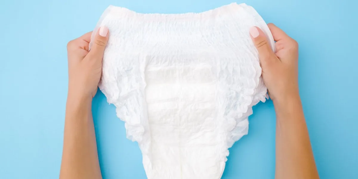 woman hands holding white adult diaper on pastel blue background closeup point of view shot top view