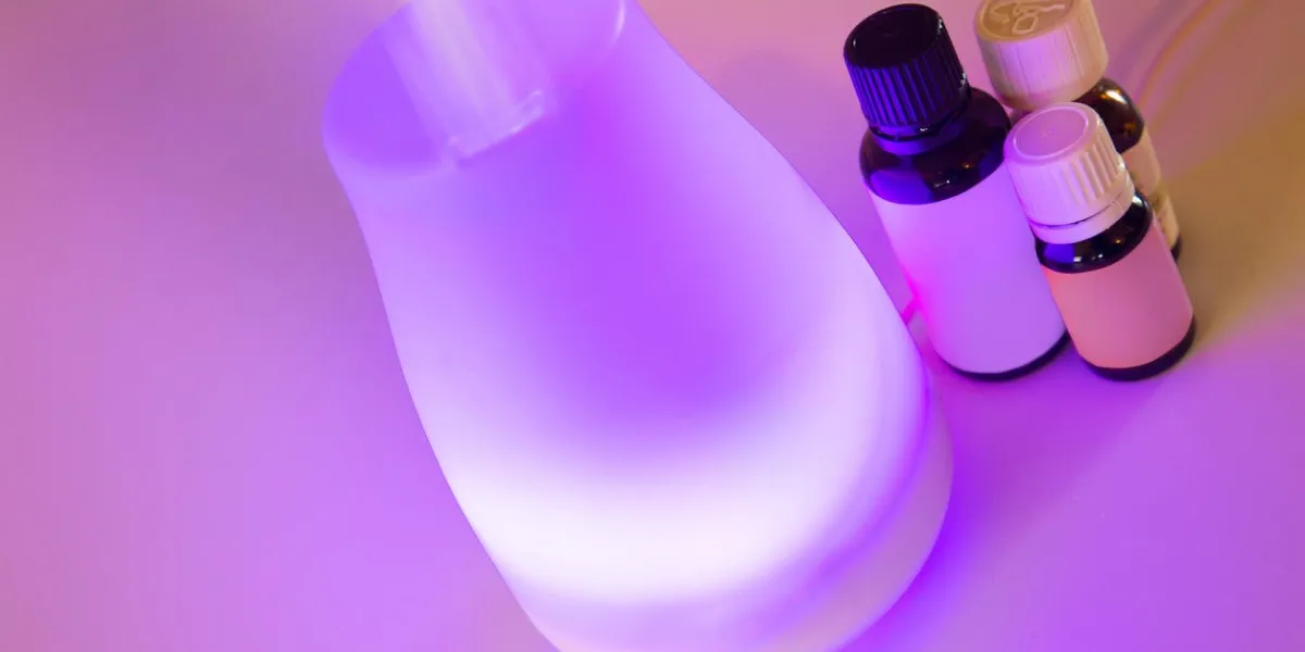 aromatherapy essential oil diffuser with purple light and oil bottles