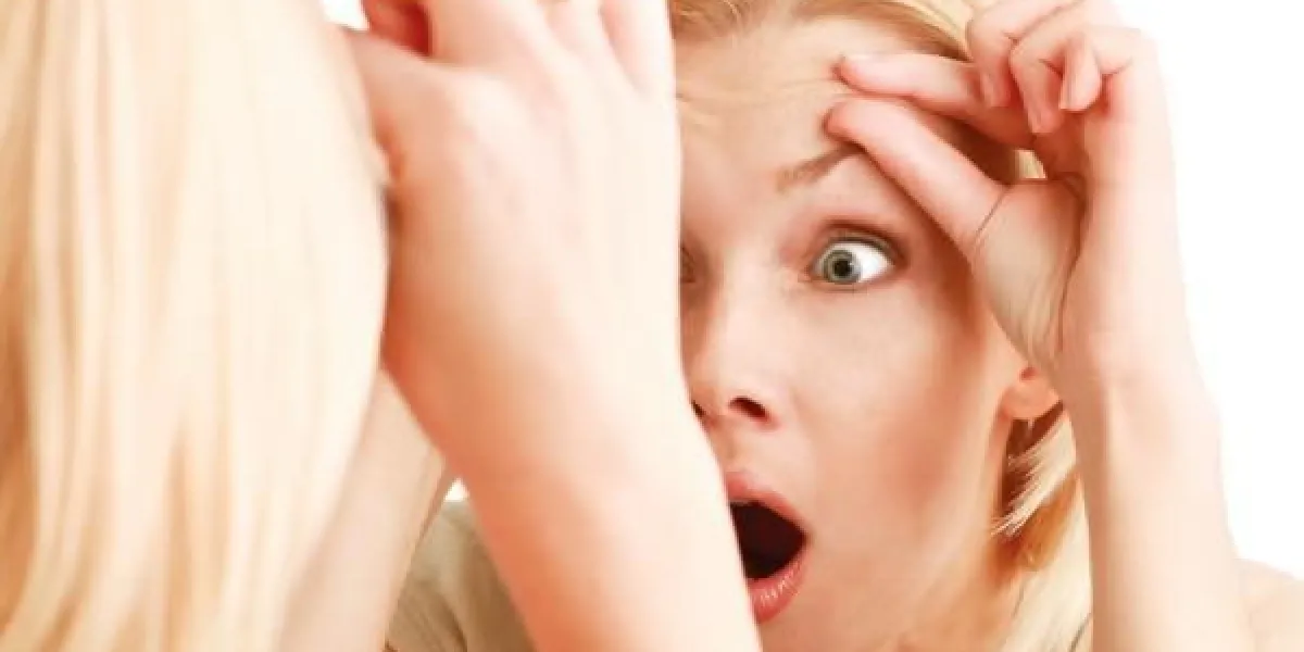 choqué jeune femme vérifiant ses rides sur son front