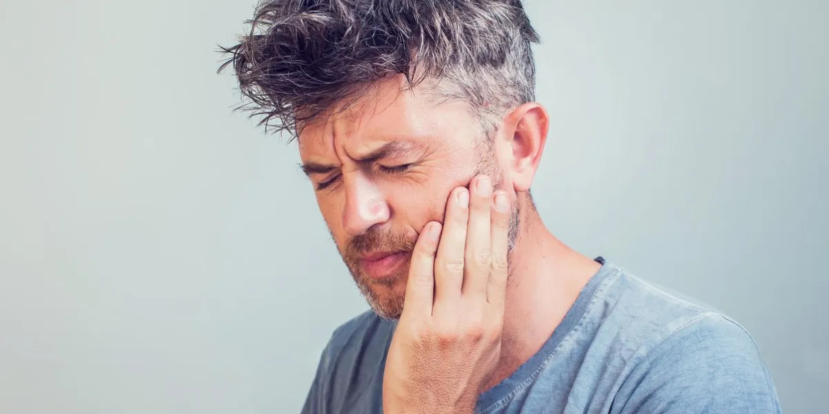 man holds his hand near the cheek toothache
