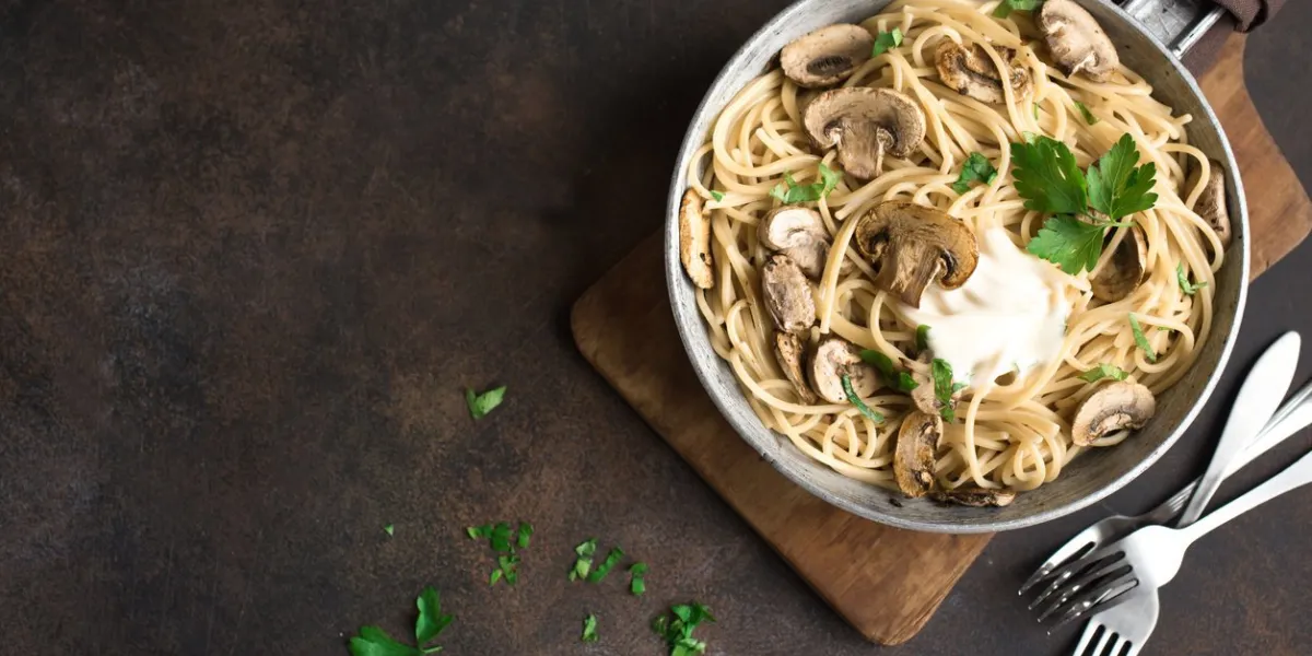mushroom spaghetti pasta and cream sauce on rustic background, top view homemade italian pasta with champignon mushroom in cooking pan