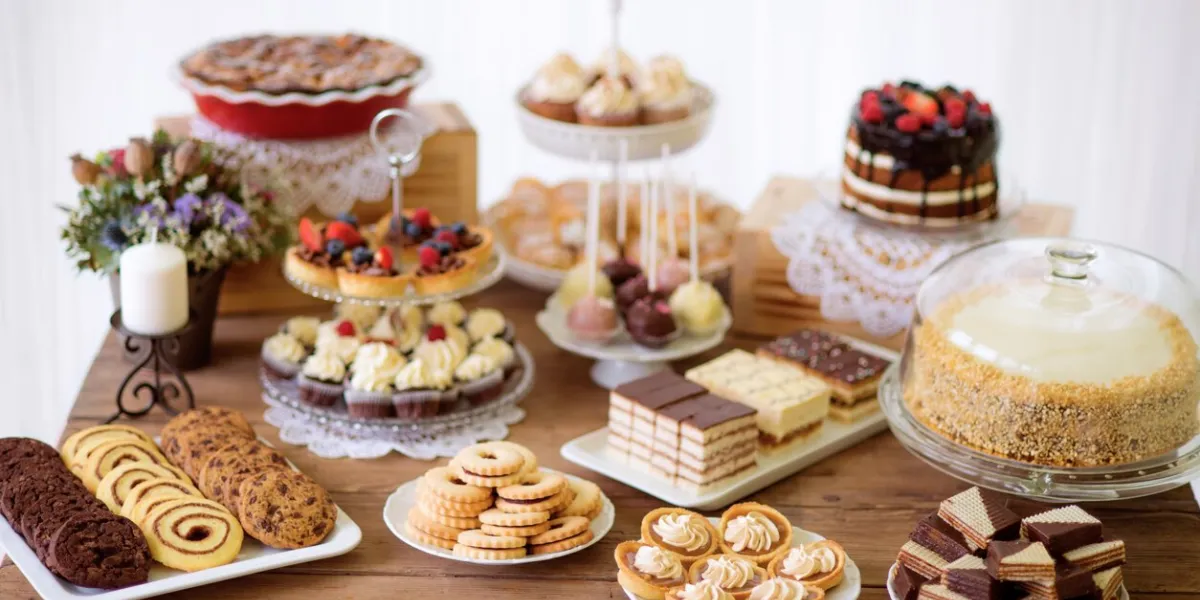 brown wooden table with various cookies, tarts, cakes, cupcakes and cakepops studio shot
