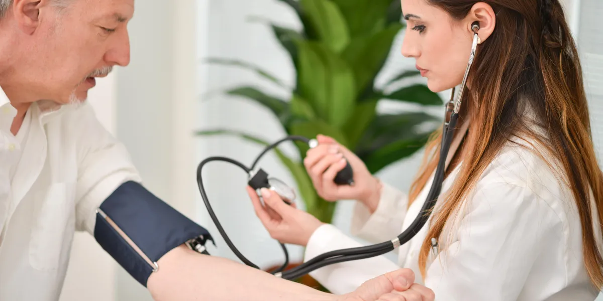 doctor using a stethoscope and a sphygmomanometer to check blood pressure
