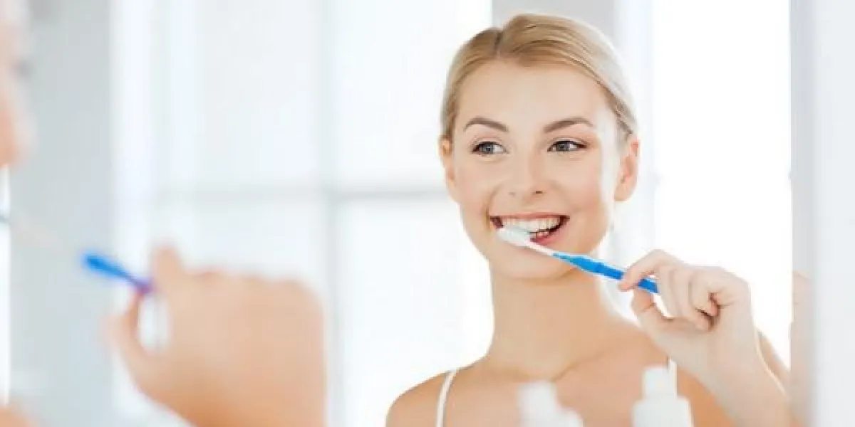 concept de soins de santé, d'hygiène dentaire, de personnes et de beauté - souriante jeune femme avec brosse à dents, nettoyage des dents et de regarder à la maison de miroir